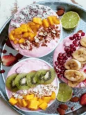 Exotic Tropical Smoothie Bowls with spoons and fruits, perfect for a refreshing and healthy treat.